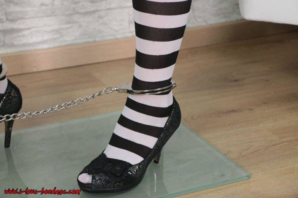 Fair skinned girl is restrained by cuffs at wrists and ankles in striped socks - #12