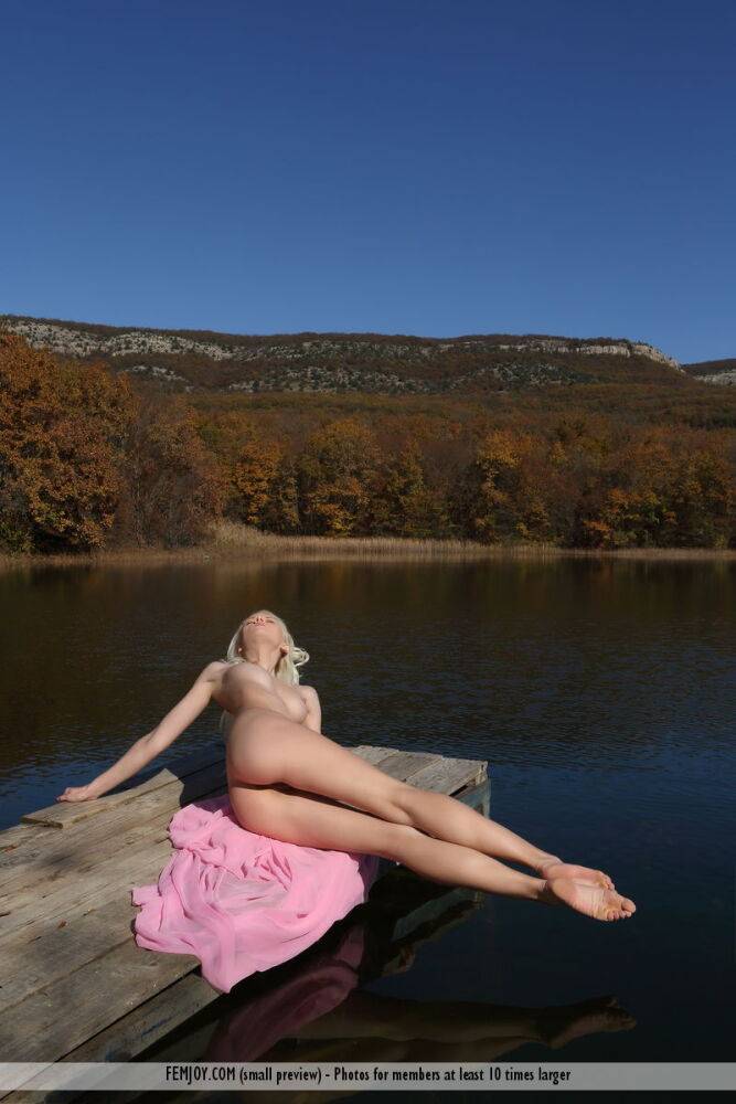 Blonde teen Adelia B strikes great nude poses on a lawn near a body of water - #9