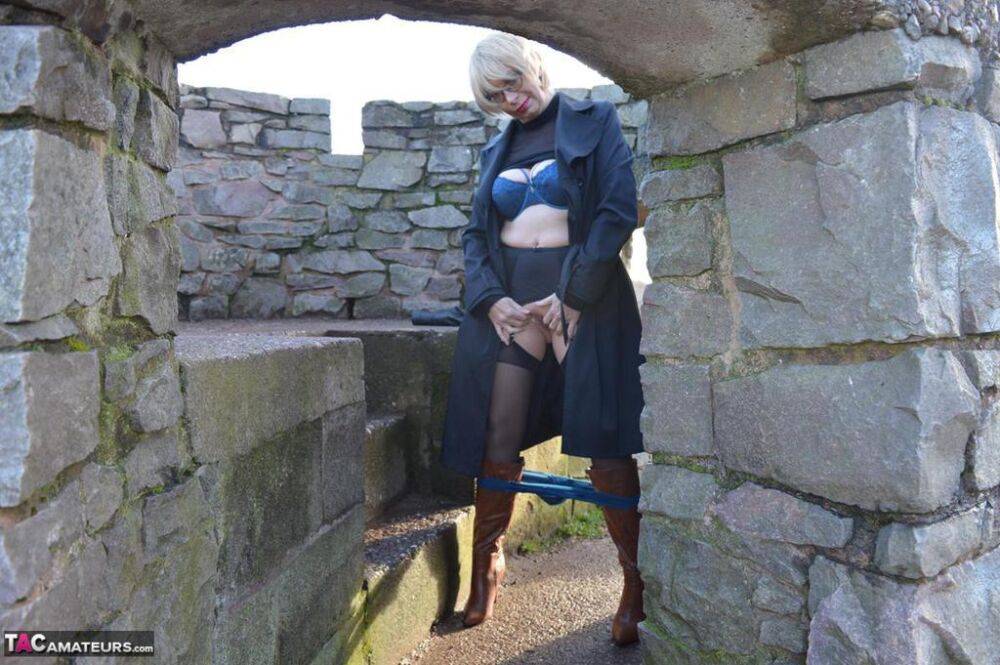 Mature blonde Barby Slut exposes her tits and twat in leather coat by a river - #11