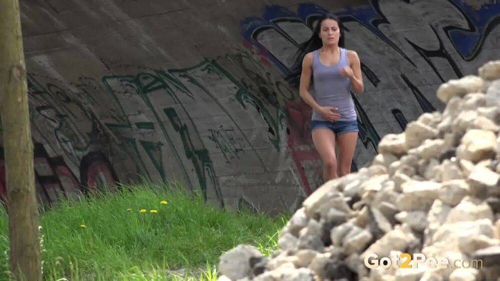 Dark haired traveler Lexi looks for a place to pee and pisses under a bridge - #6