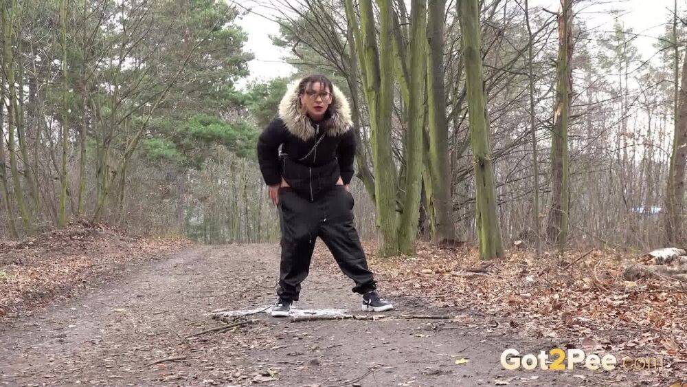 Solo girl Natasha Ink squats for a pee on a dirt road in glasses and a coat - #1