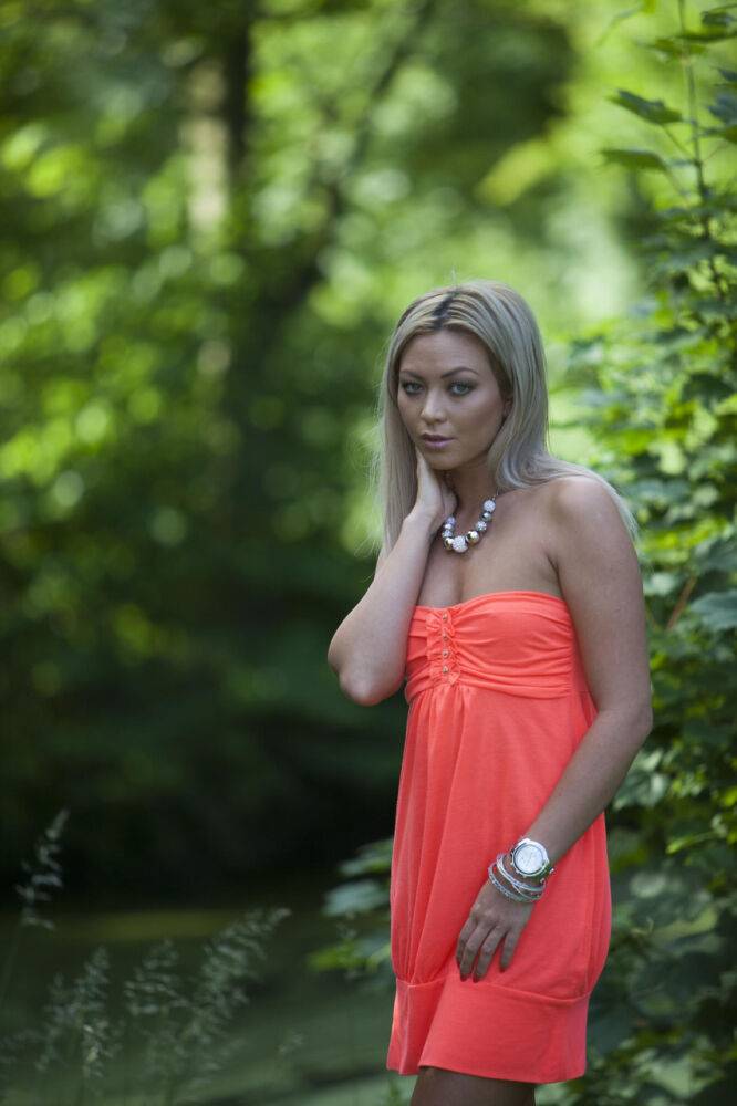 Natural blonde Natalia Forrest displays her MK watch up against a hedge - #14