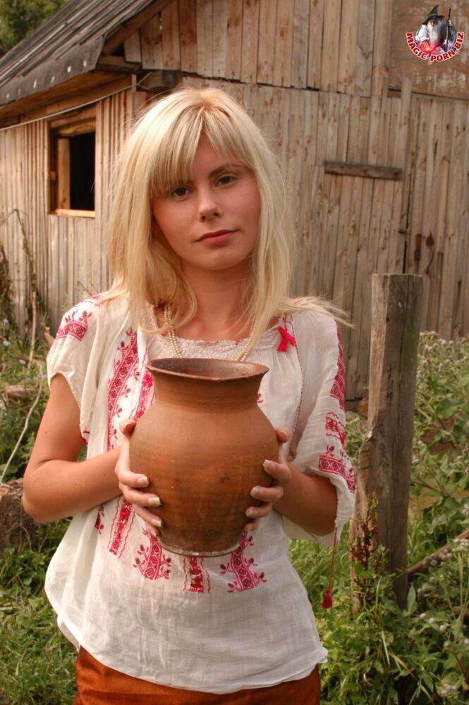 Skinny blonde leans against a stack of hay while pouring milk over her body - #5