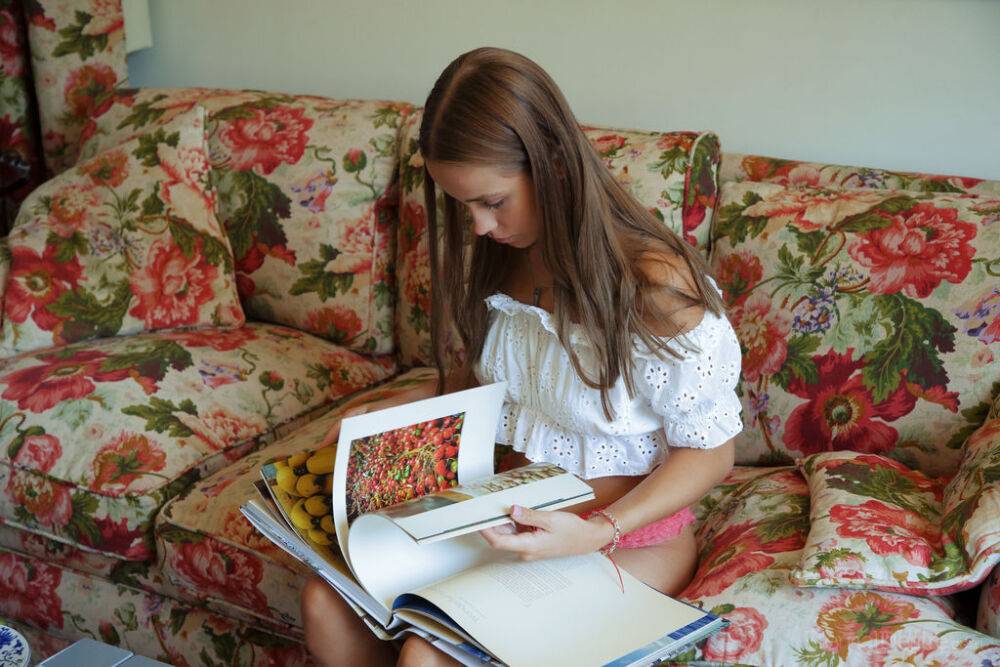 Nice teen Cassia flips thru a book before posing naked on a chesterfield - #7