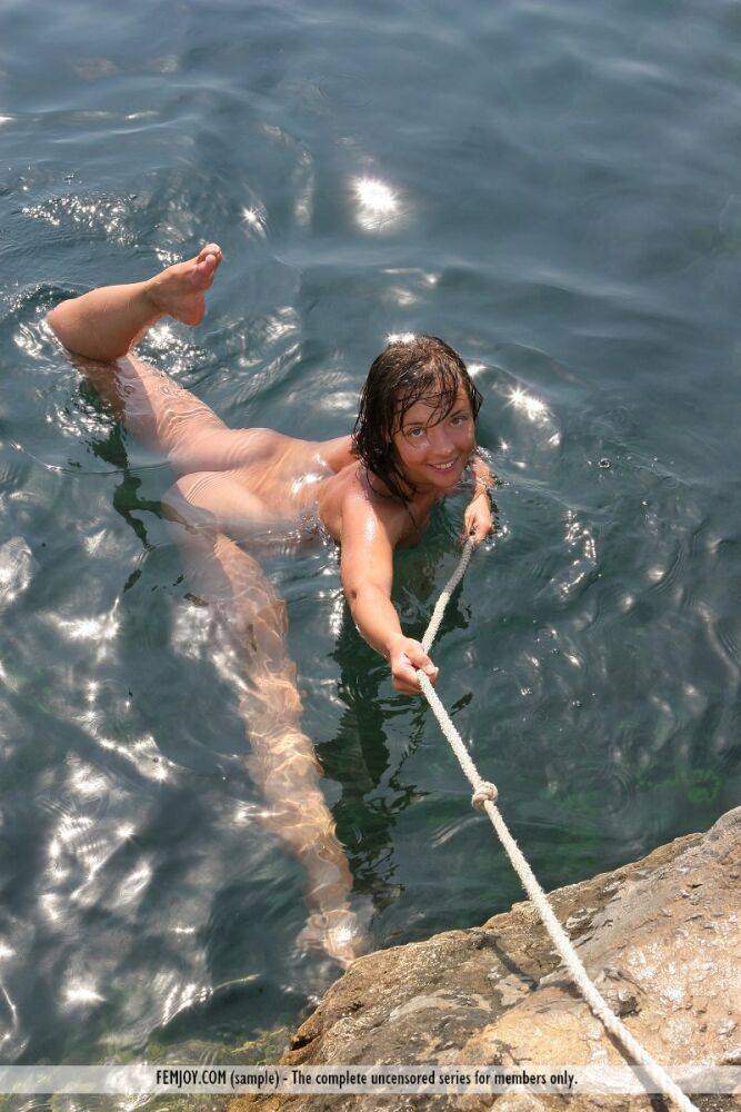 Totally naked beauty Kalinka holds a rope while slipping into the sea - #6