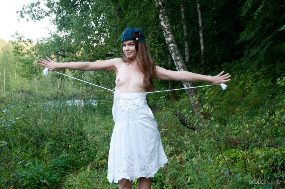 Cute teen Nedda A takes off a white dress to pose nude on a fallen tree - #13