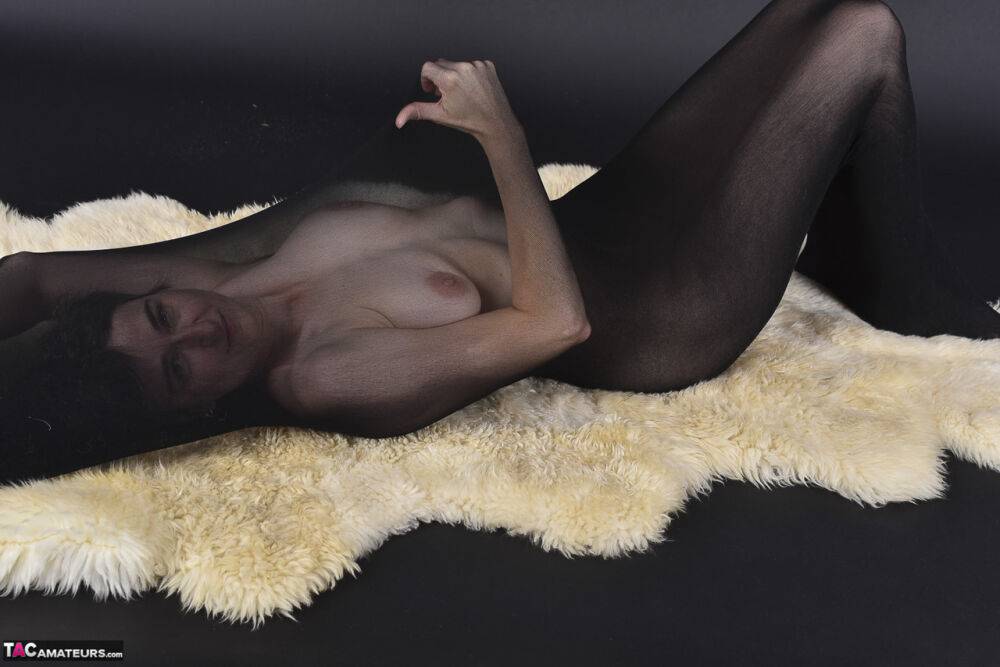 Naked mature woman encases herself in a stocking atop a rug - #6