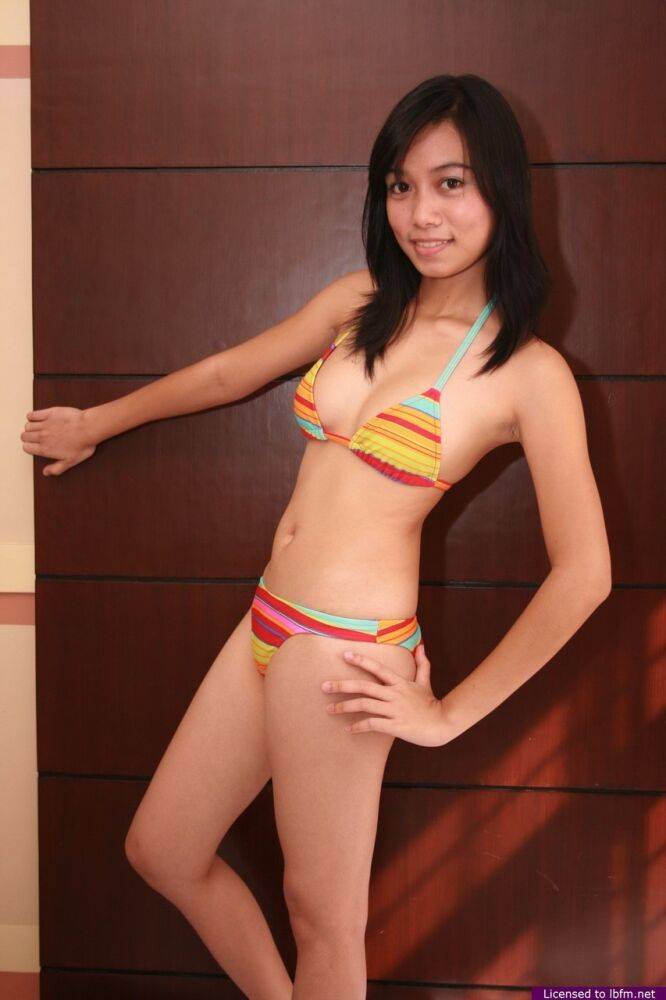 Asian teen Janelyn works free of her bikini to pose nude upon a bed - #1