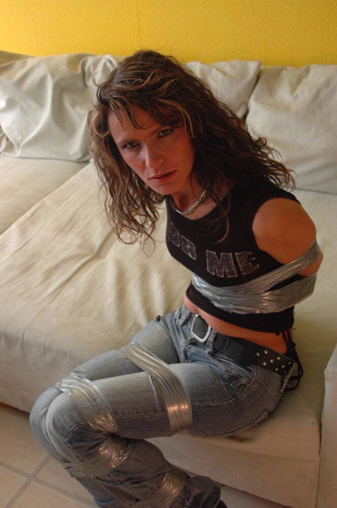 Clothed female is silenced and restrained with duct tape on a sofa - #8