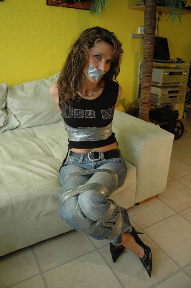 Clothed female is silenced and restrained with duct tape on a sofa - #2