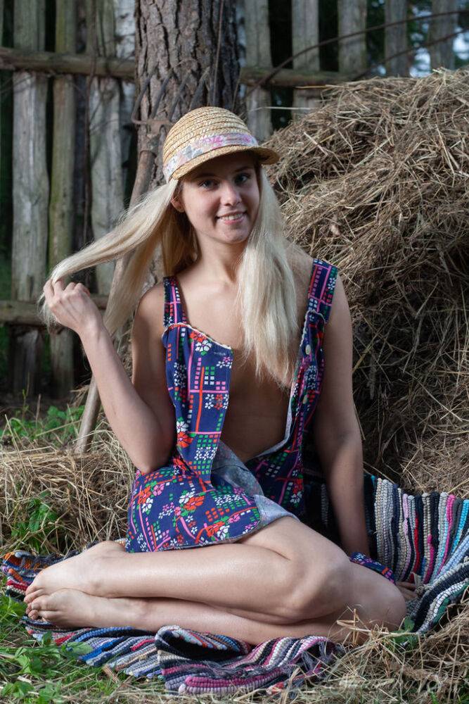 Young blonde Agnes H doffs a dress to get naked on weathered straw in a yard - #6