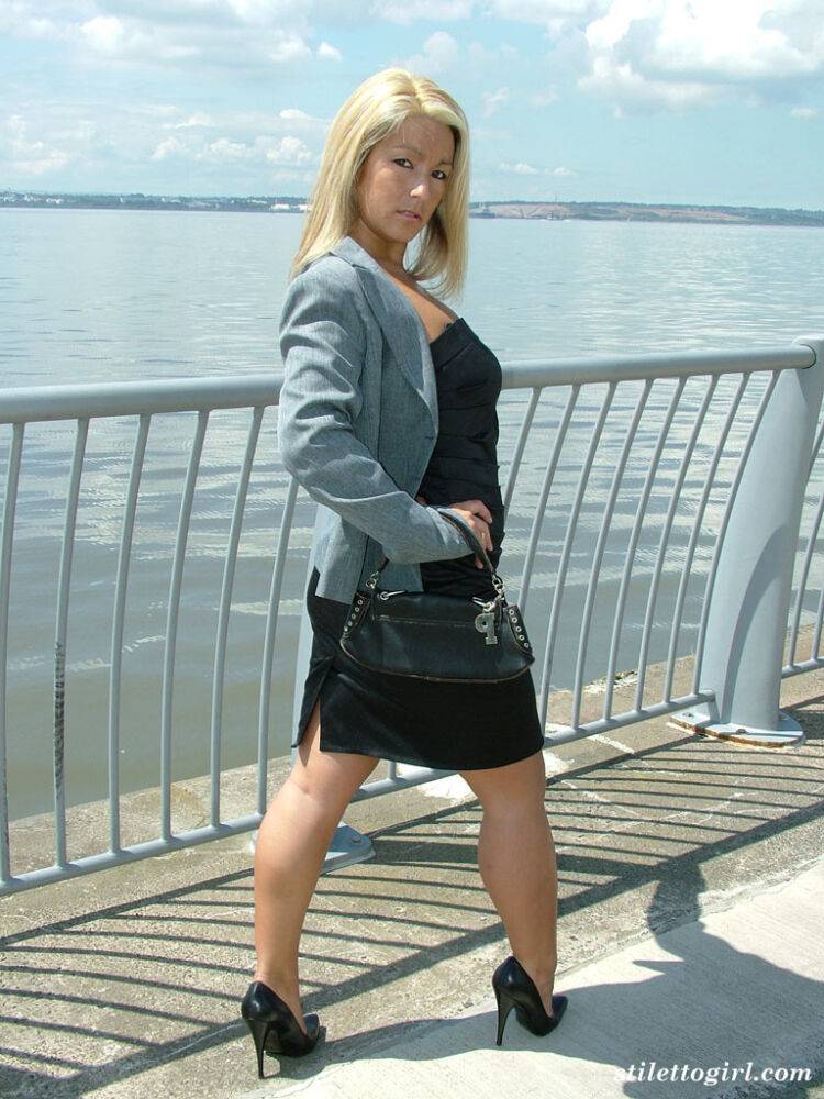 Blonde woman in black dress and pumps goes for a walk near the ocean - #12