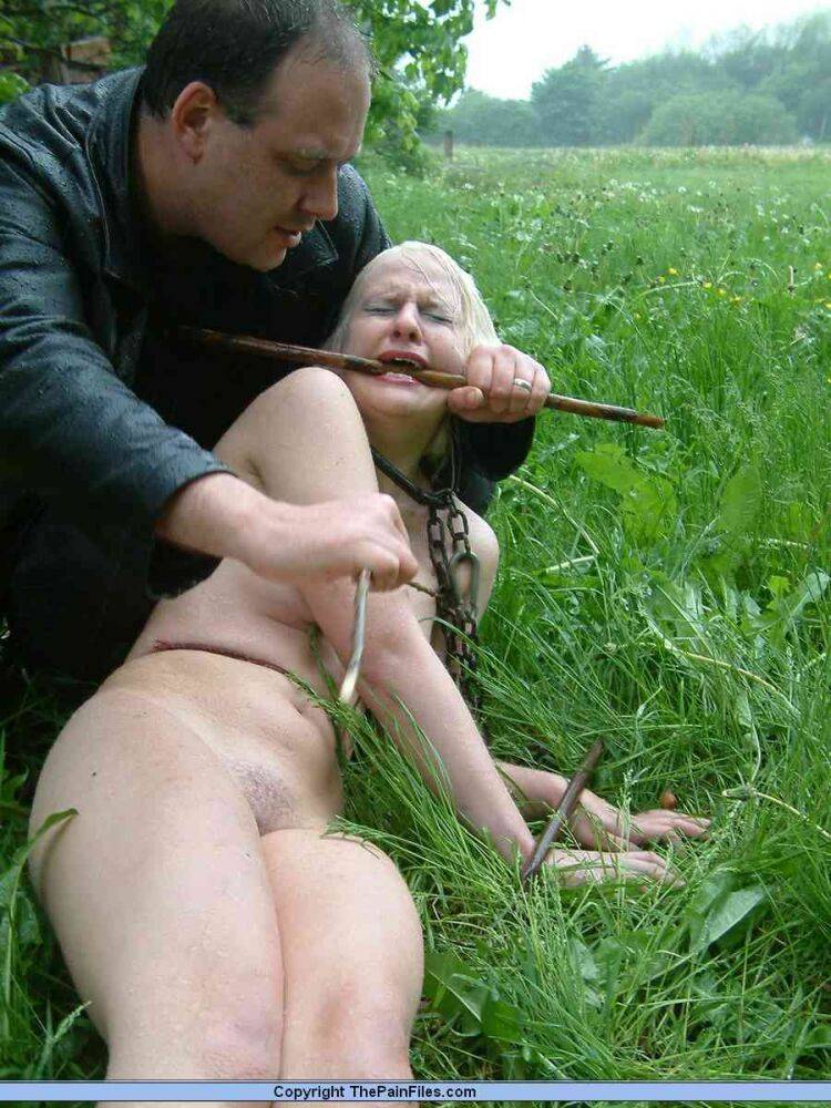 Naked blonde slave is caned and stomped on in a field of lush grass - #2