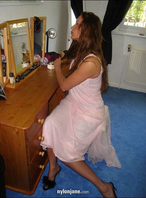 Older woman brushes her long hair in a mirror wearing nylons and garter belt - #10