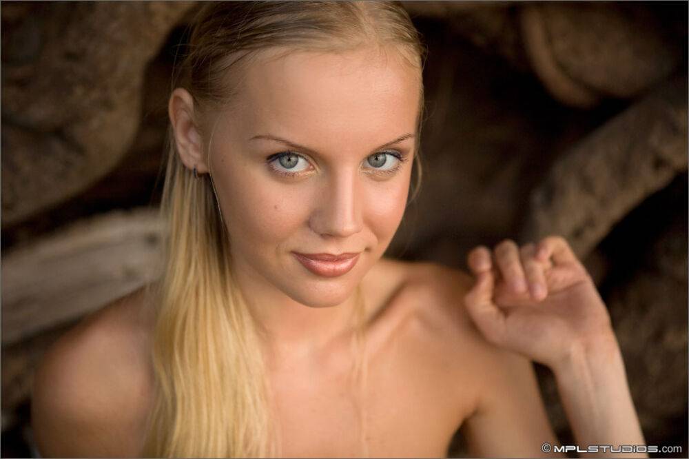 Skinny blonde removes a wrap to pose nude inside a sea cave - #7