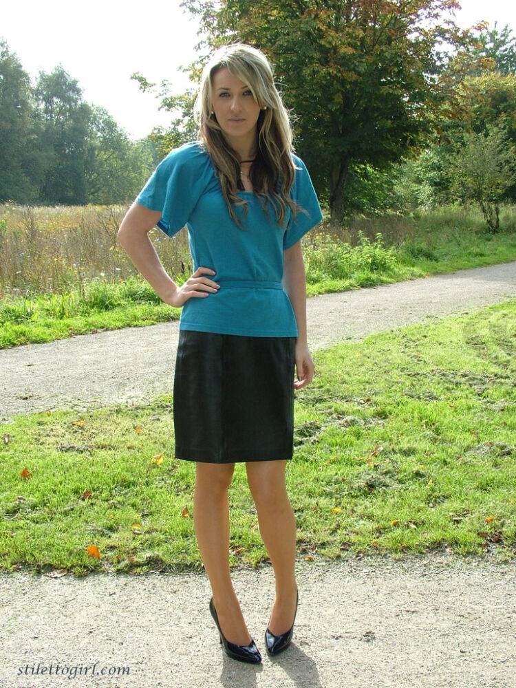 Clothed woman shows off her shapely legs outdoors in a skirt and black pumps - #5