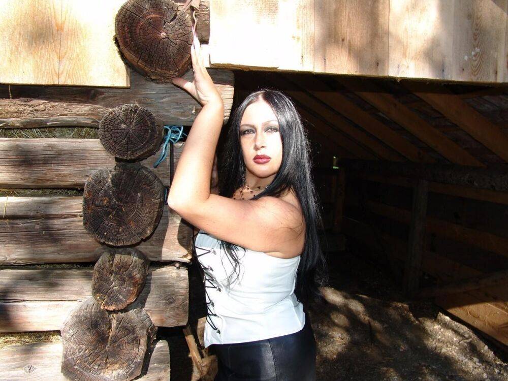 Dark-haired goth Lady Angelina shows her big tits and pussy by a log building - #5