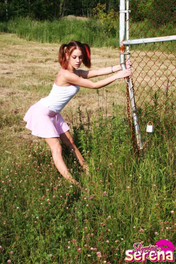 Young redhead Stunning Serena slips a skirt over her thong clad ass in a field - #9