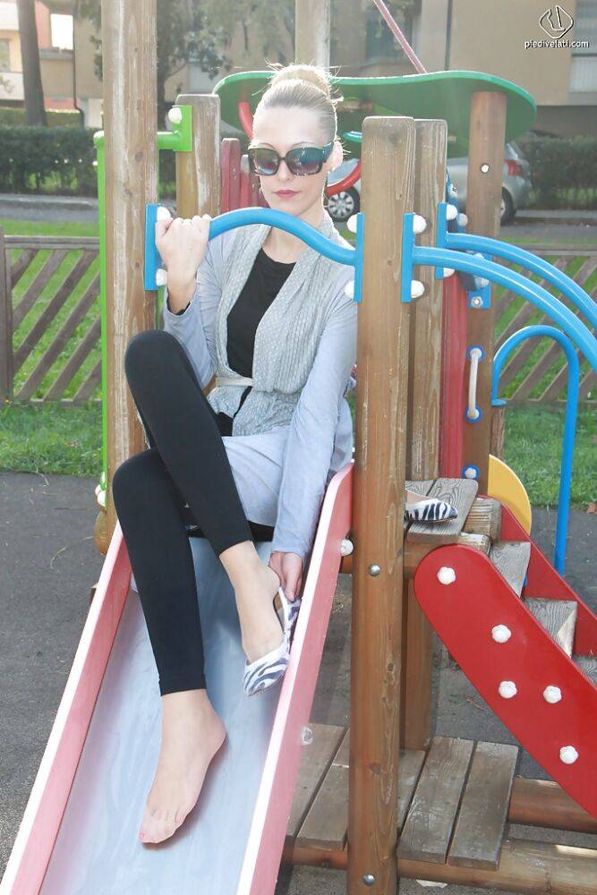 Lovely Christelle is showing her fine feet on a children playground - #1
