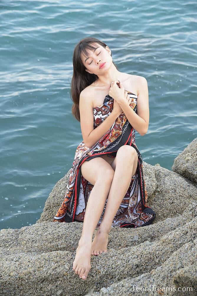 Young Asian girl Sowan models completely naked on weathered rocks by the water | Photo: 2674008