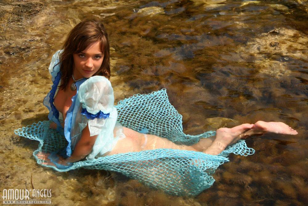 Adorable young girl Lisa models nude on fisherman's net in shallow water - #14