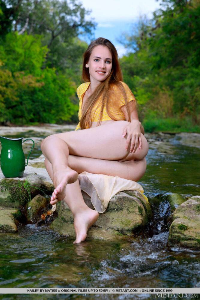 Young redhead Hailey models in the nude upon a rock in a stream - #6