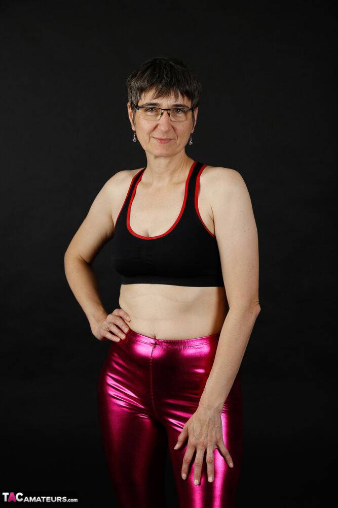 Mature woman models a sports bra in shiny pants and black boots - #15