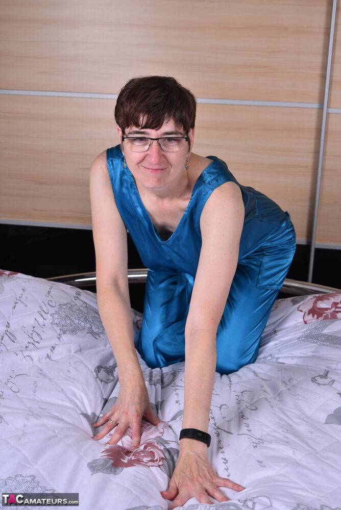 Amateur woman models satin evening wear on a bed with her glasses on - #12