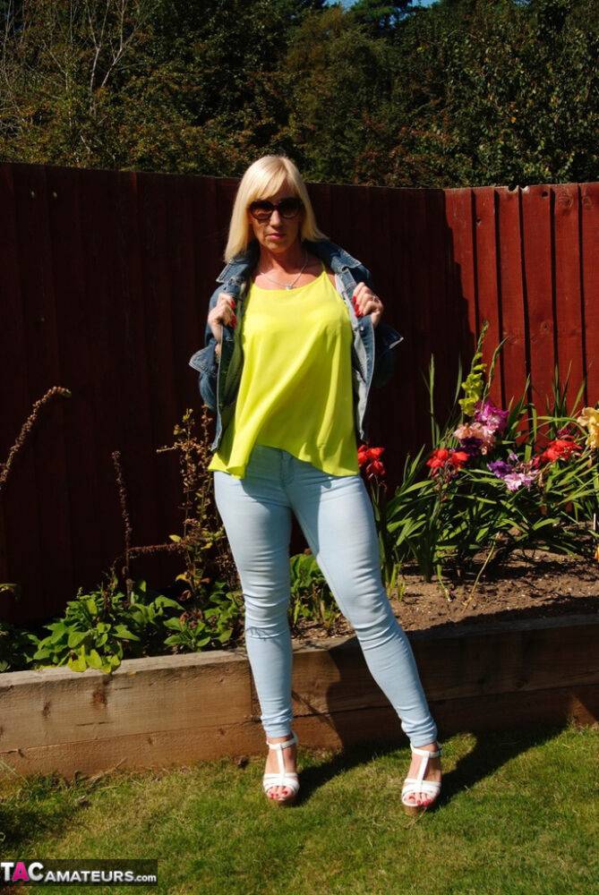 Middle-aged blonde Melody models in a bra and faded jeans in a backyard - #14