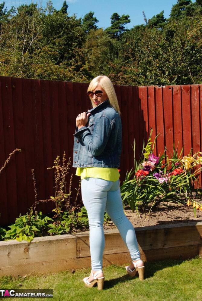 Middle-aged blonde Melody models in a bra and faded jeans in a backyard - #5