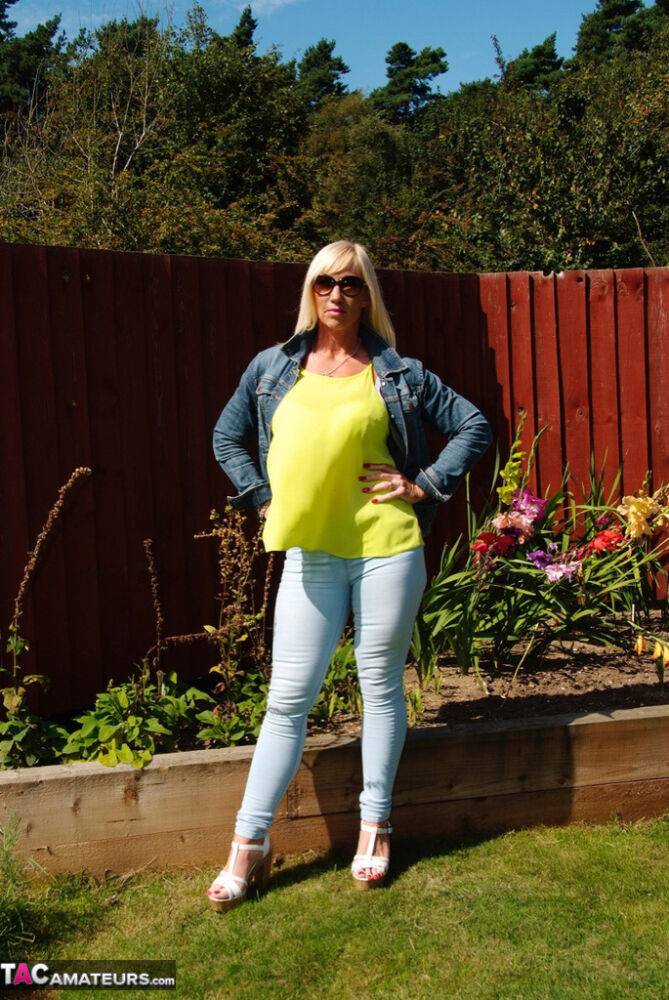 Middle-aged blonde Melody models in a bra and faded jeans in a backyard - #13