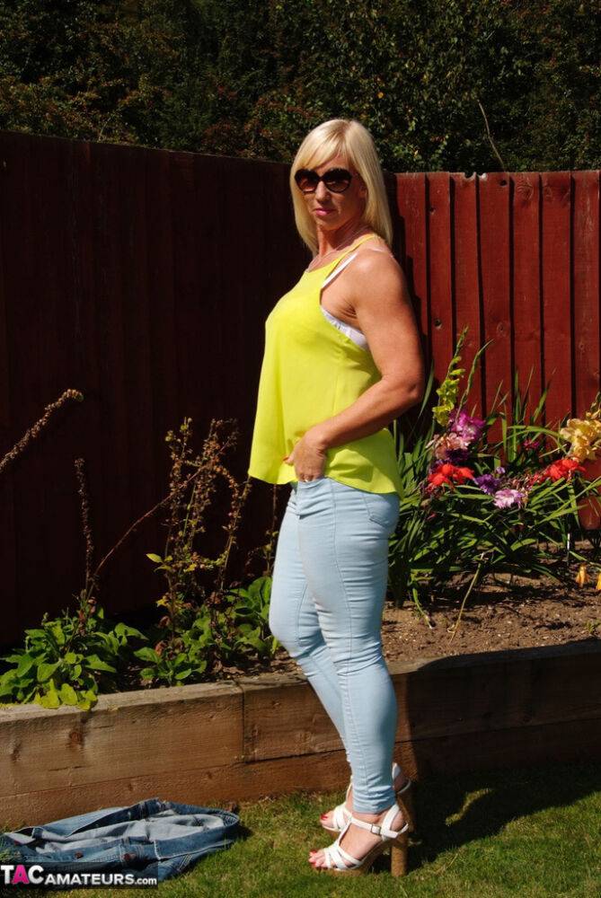 Middle-aged blonde Melody models in a bra and faded jeans in a backyard - #6