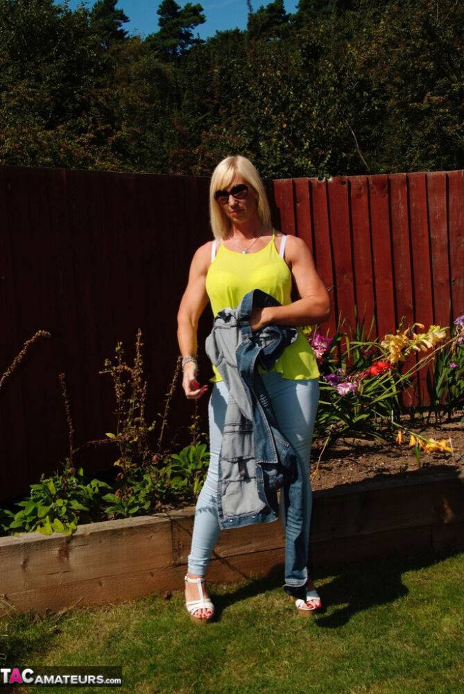 Middle-aged blonde Melody models in a bra and faded jeans in a backyard - #2