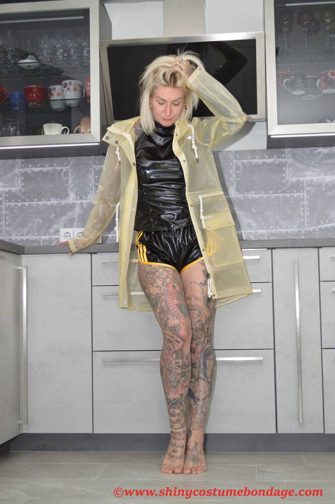 Tattooed blonde Miss Francine models barefoot in a raincoat over rubber wear - #15