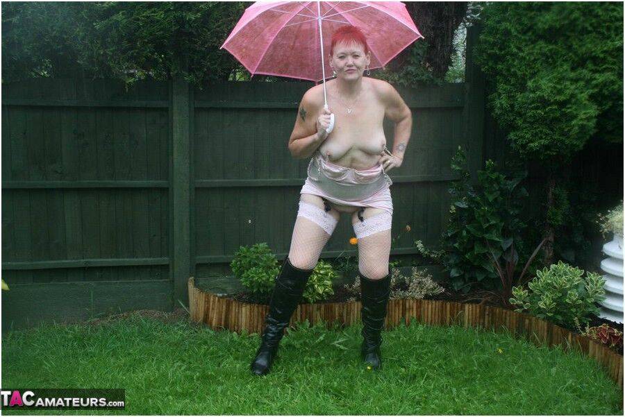 Older redhead Valgasmic Exposed models nude in the rain while holding a brolly - #1