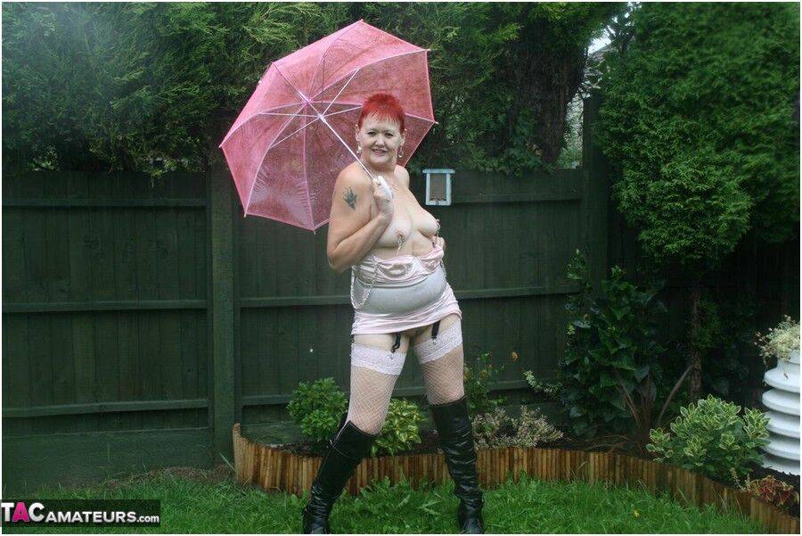 Older redhead Valgasmic Exposed models nude in the rain while holding a brolly - #4
