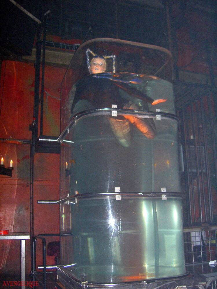 Caucasian female Dark Wing models latex apparel while in a watery cage - #7