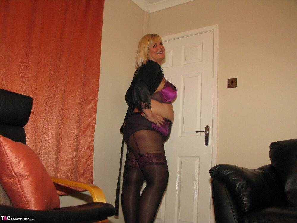 Older blonde BBW Chrissy Uk models lingerie & pantyhose on a leather loveseat - #1