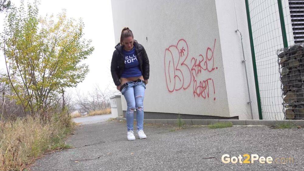 Czechoslovakian female Naomi Bennet takes a pee on pavement beside a building - #12