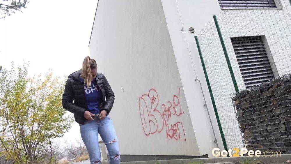 Czechoslovakian female Naomi Bennet takes a pee on pavement beside a building - #6