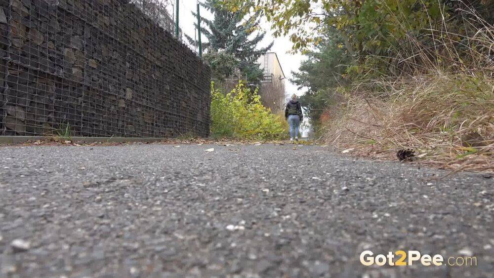 Czechoslovakian female Naomi Bennet takes a pee on pavement beside a building - #3