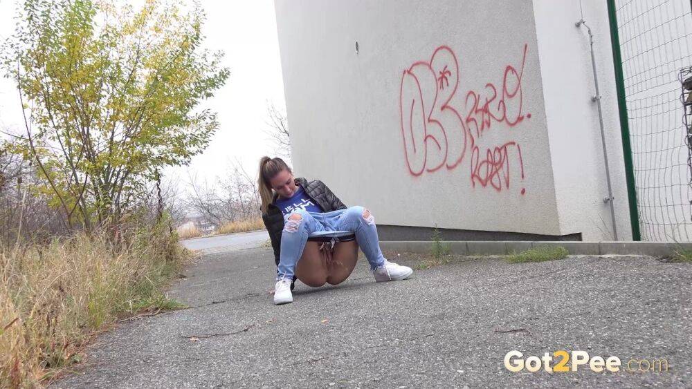 Czechoslovakian female Naomi Bennet takes a pee on pavement beside a building - #9