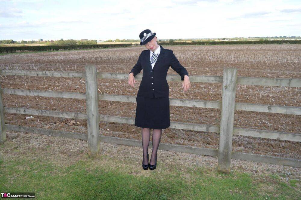 Mature policewoman Barby Slut removes her uniform against a fence at a farm - #1