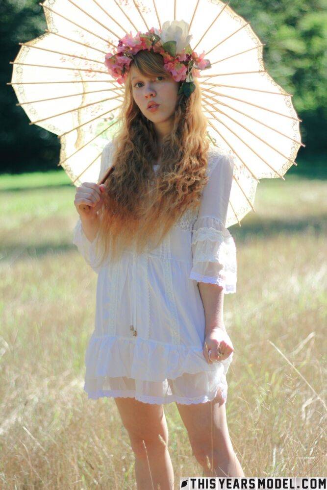 Charming redheaded teen Dolly Little holds a parasol while getting naked - #8