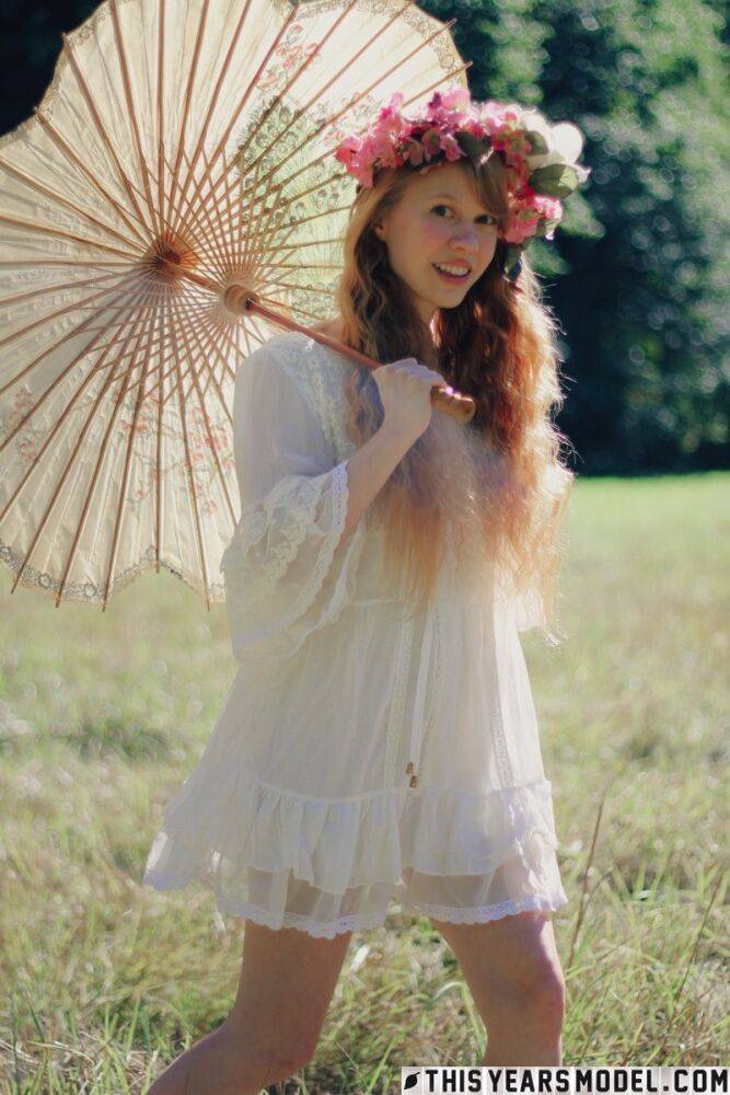 Charming redheaded teen Dolly Little holds a parasol while getting naked - #7