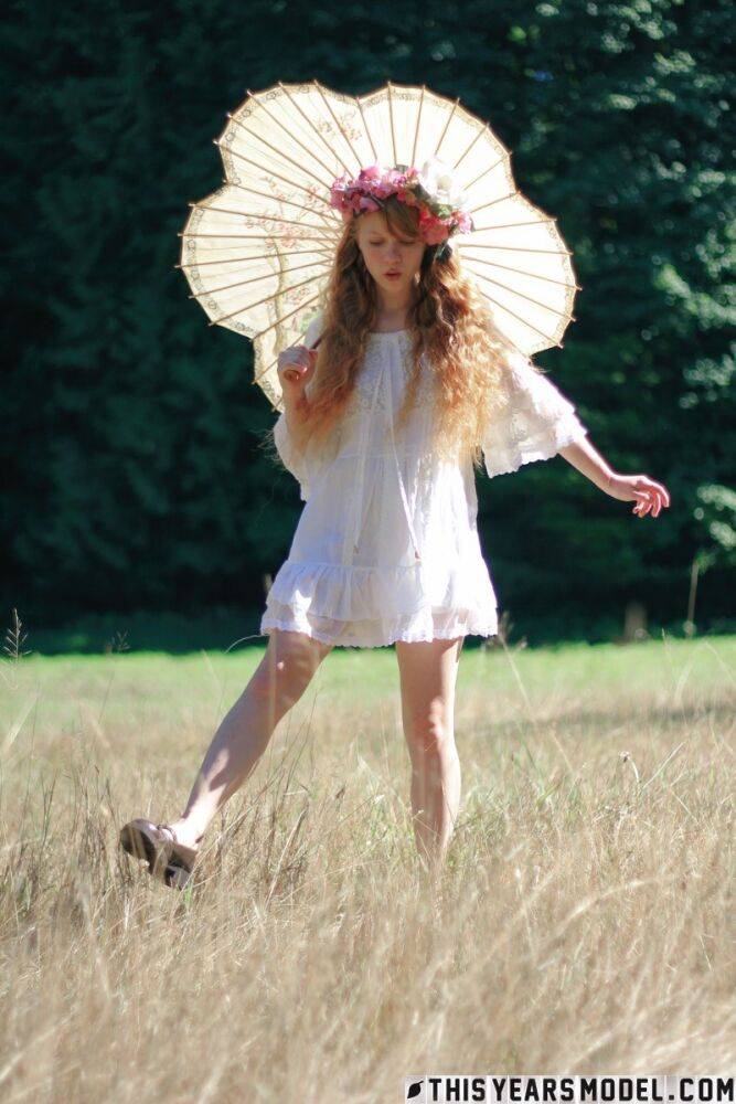 Charming redheaded teen Dolly Little holds a parasol while getting naked - #14