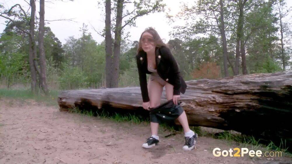 Caucasian girl Nastya squats for a pee by a rotting log on a patch of sand - #13