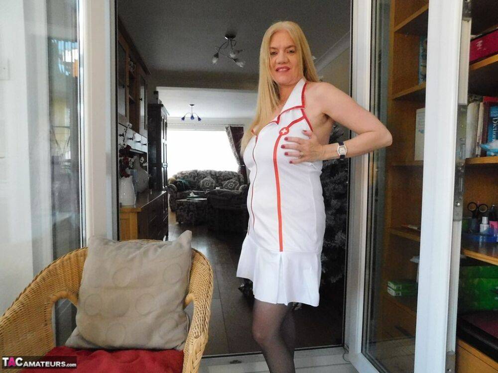 Older British nurse Lily May unzips her uniform on a wicker chair - #11
