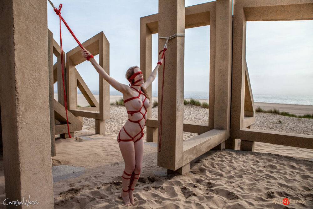 White girl Carmine Worx is tied with ropes to construction beams on a beach - #13