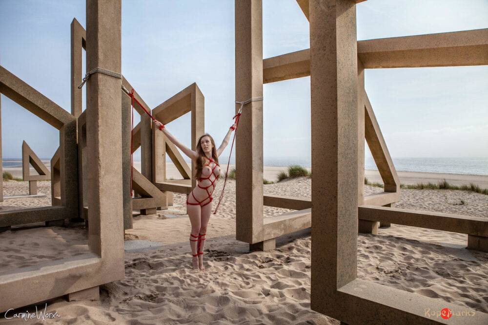 White girl Carmine Worx is tied with ropes to construction beams on a beach - #15